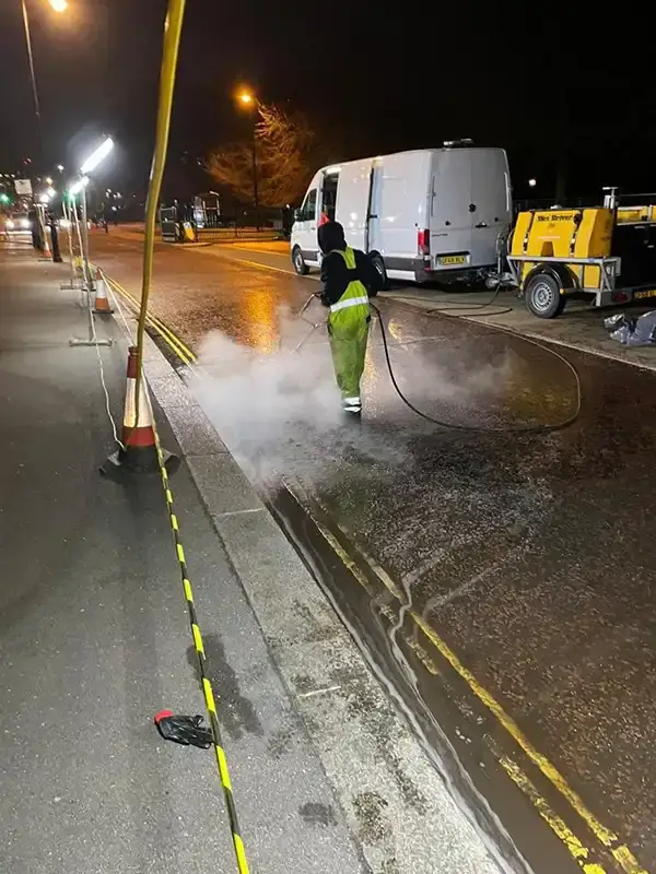 A technician using a rotary scrubber to clean oil from a road in Hyde Park, London.