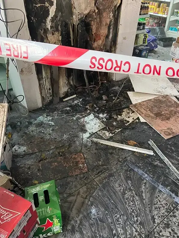 Soot and fire damaged retail unit with red and white tape blocking the entrance.