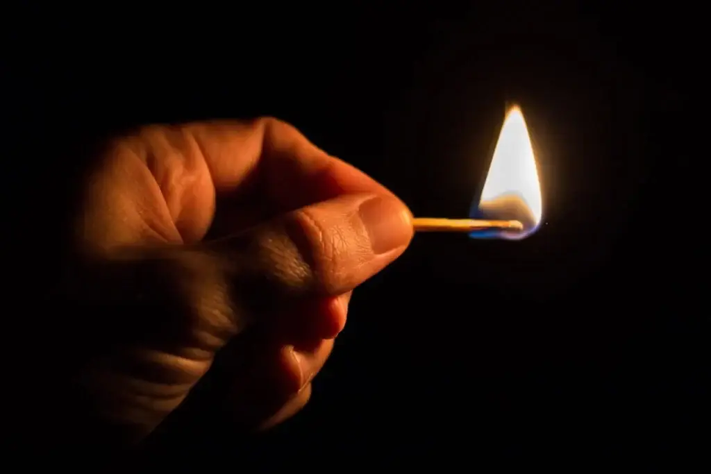 A hand holding a burning match.