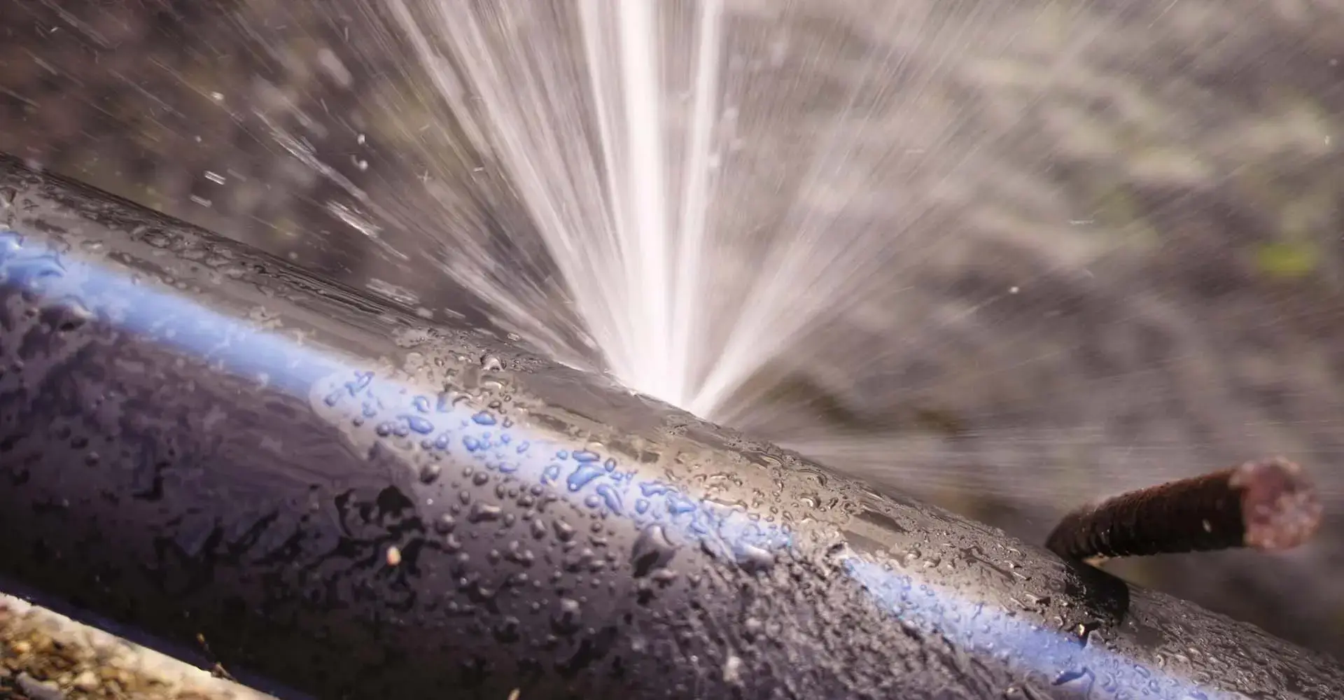 A burst water pipe spraying out pressurised water.